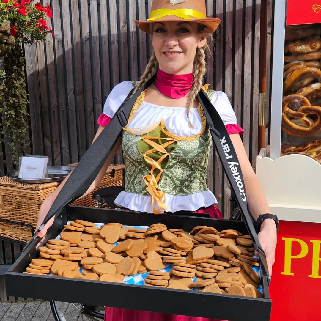 Fresh gingerbread cookies for sale at a festive market, held by a woman in traditional Bavarian dress.