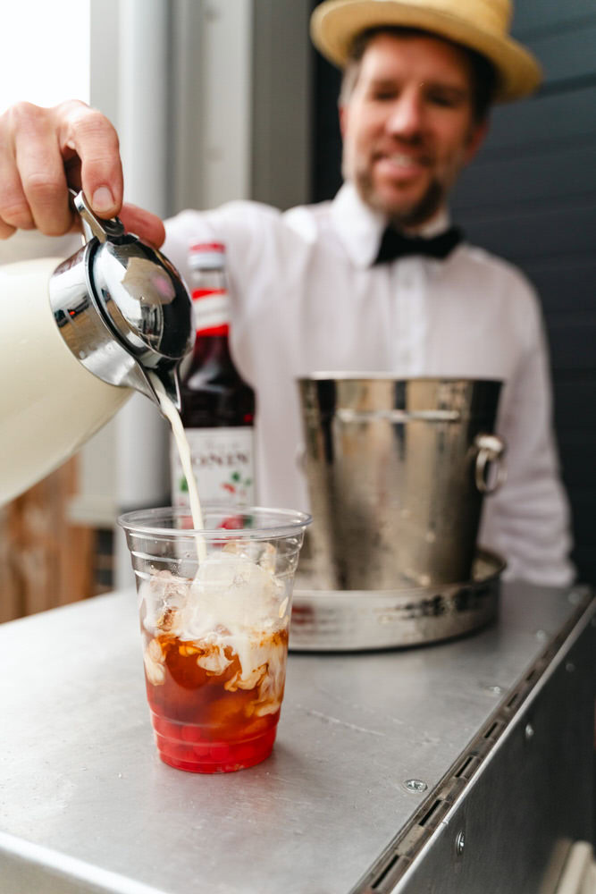 Creamy iced coffee being prepared with milk and syrup for a refreshing summer drink.